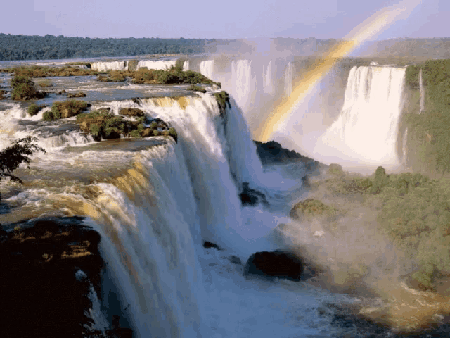 a waterfall with a rainbow in the sky above it