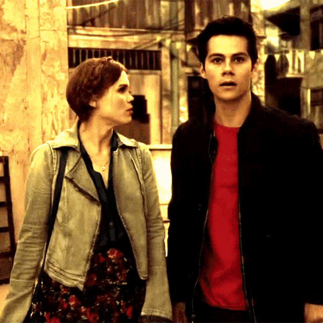 a man in a red shirt stands next to a woman in a white jacket