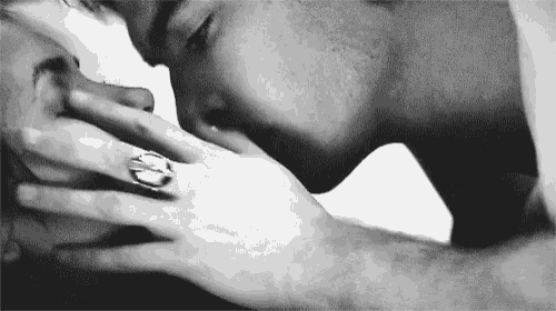 a black and white photo of a man kissing a woman on the neck .