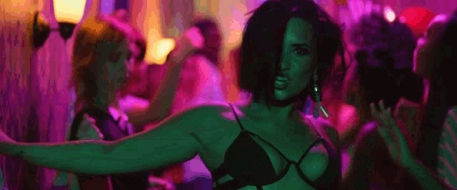 a woman in a black bra is dancing in a crowd of people in a club .