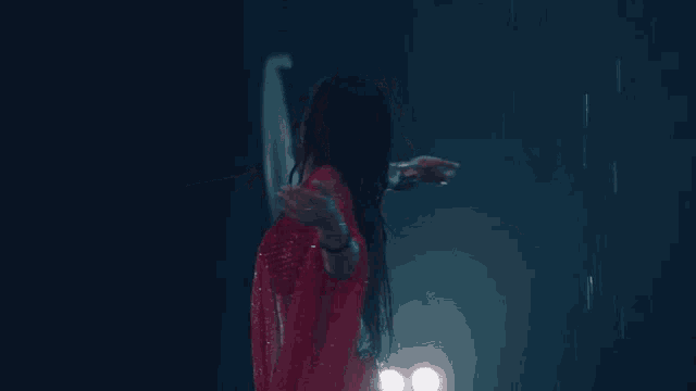 a woman in a red top and skirt is dancing in the rain