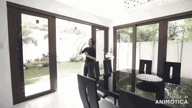 a woman is standing in a dining room with a black table and chairs
