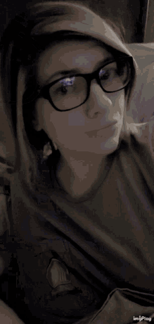 a woman wearing glasses and a hoodie has a watermark that says imgplay on the bottom