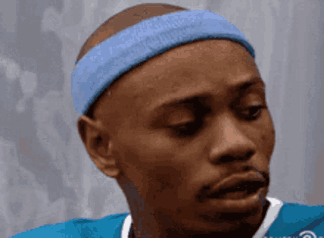 a man wearing a blue headband and a blue shirt is making a funny face