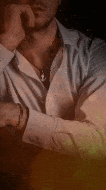 a man in a white shirt has an anchor necklace