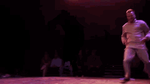 a man in a white shirt is dancing on a stage in front of a crowd