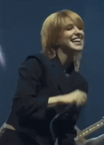 a woman singing into a microphone in front of a blue background