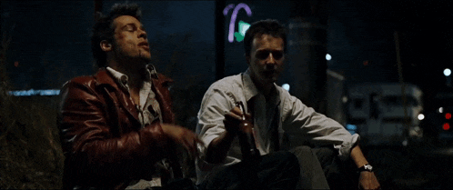 a man in a red jacket sits next to a man in a white shirt