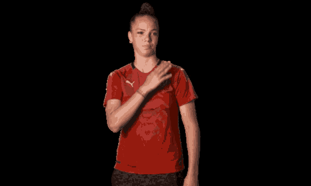 a woman is wearing a red puma shirt with a lion on it
