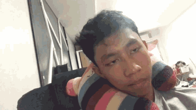 a young man laying on a couch with a striped pillow on his head