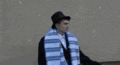 a man wearing a hat and a scarf is standing in the snow .