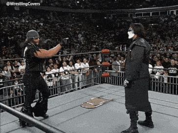 two wrestlers are standing in a ring with a chair on the floor in front of them