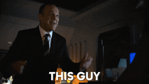 a man in a suit and tie is standing in front of a sign that says this guy
