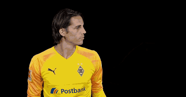 a man wearing a yellow postbank jersey holds up his hand
