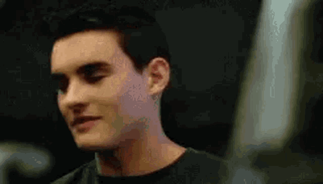 a close up of a man 's face in a black shirt looking at the camera .