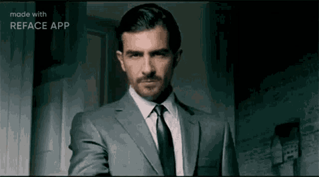 a man in a suit and tie is standing in front of a door and looking at the camera .