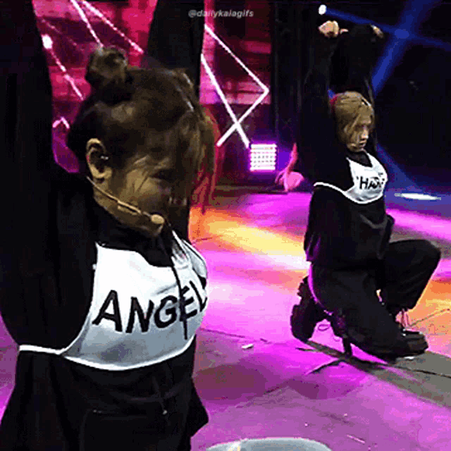 a woman wearing a vest that says angel is dancing on a stage