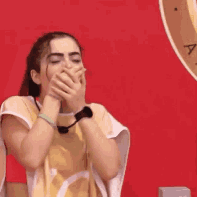 a woman is covering her mouth with her hands .