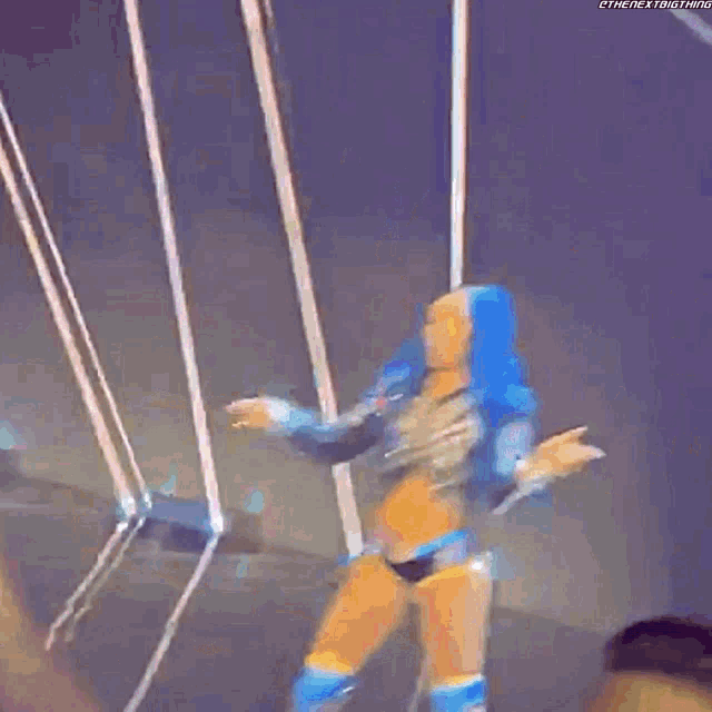a woman in a wrestling outfit is dancing on a stage while a man takes a picture of her .
