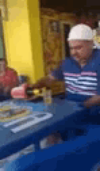 a man wearing a hard hat is sitting at a table in a blurry photo .