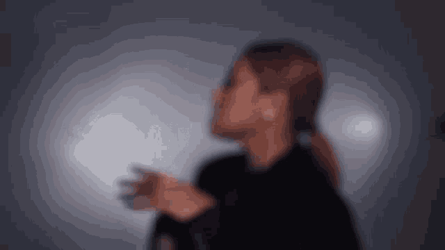 a blurry picture of a woman standing in front of a wall with her hands outstretched .