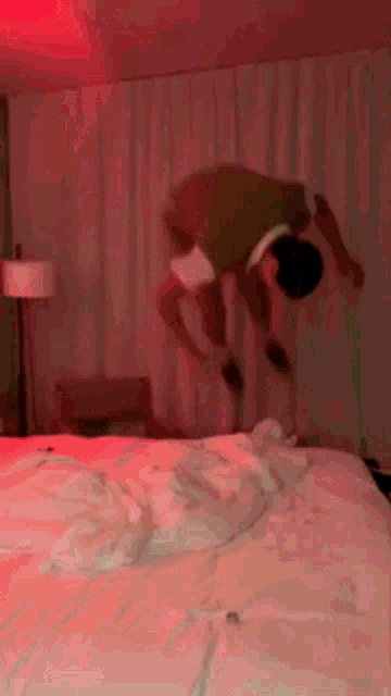 a blurry picture of a couple jumping on a bed with red lights .