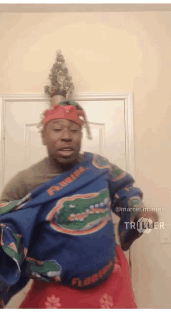 a man wearing a florida gators sweater is dancing in front of a christmas tree