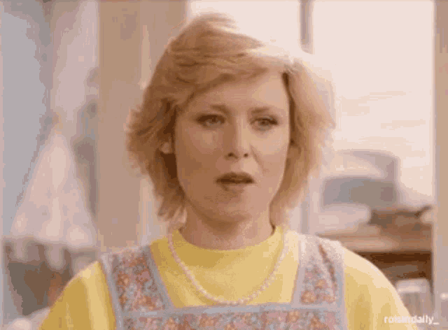 a woman is wearing a yellow sweater and a blue apron .