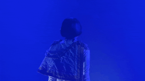 a woman is standing in front of a bright blue background