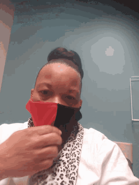 a woman wearing a red and black face mask with a leopard print scarf around her neck