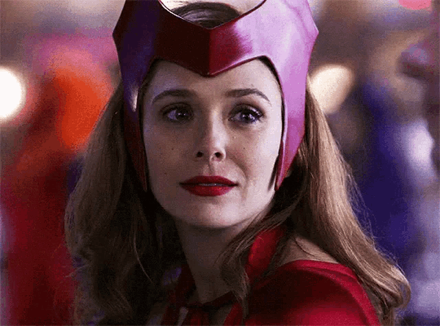a close up of a woman wearing a red cape and a red hat .