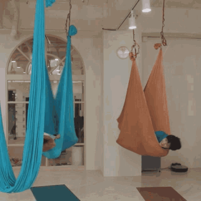 two hammocks are hanging from the ceiling in a room with a clock in the background