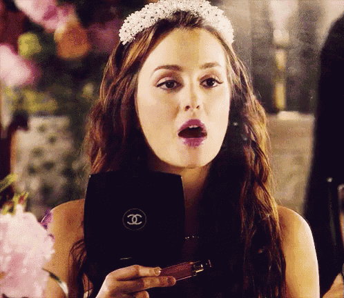 a woman with a crown on her head is holding a chanel makeup case