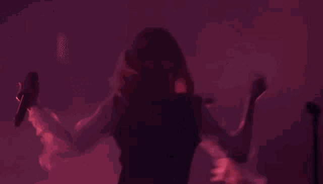 a woman is singing into a microphone while dancing on stage .