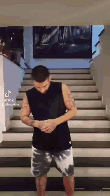 a man is standing on a set of stairs with his hands on his hips .