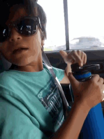 a boy wearing sunglasses and a shirt that says hawaii is sitting in a car