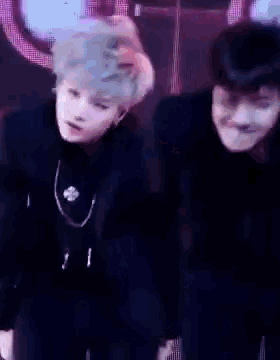 a man in a black suit is dancing on a stage with another man .