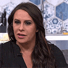 a woman with long brown hair is wearing a black shirt with a microphone on her neck .