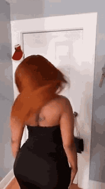 a woman in a black dress is standing next to a door .