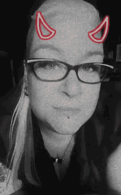 a woman wearing glasses and devil horns on her forehead .
