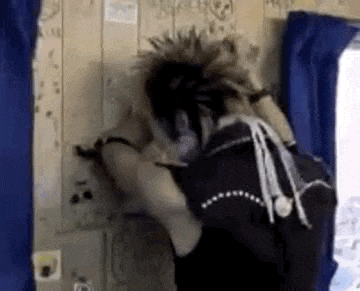 a person with a mohawk is standing in front of a wooden wall in a room .
