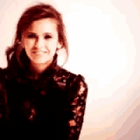a woman in a black lace shirt smiles for the camera