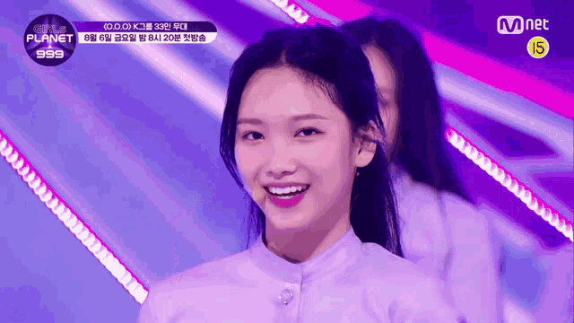 a girl in a purple shirt is smiling in front of a mnet advertisement