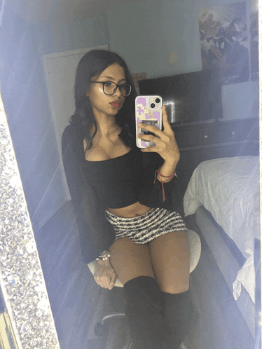 a woman taking a selfie in front of a mirror with her phone