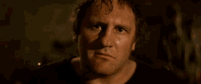 a close up of a man 's face in a dark room with a serious look on his face .