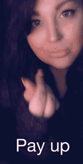 a woman with a nose ring and a pay up sign below her