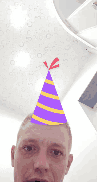a man is wearing a purple and yellow party hat on his head
