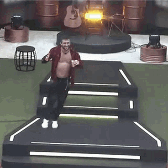 a man without a shirt is standing on a stage holding a cup