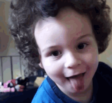 a little boy with curly hair is sticking out his tongue