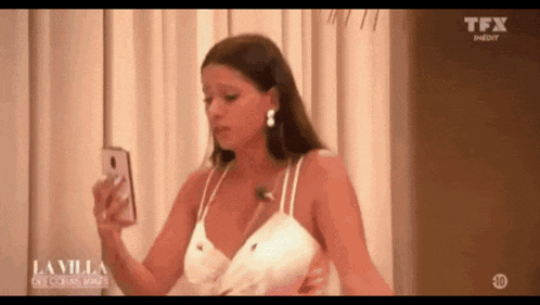 a woman in a white dress is taking a picture of herself with her cell phone .